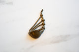 Side view of the vintage bronze musical instrument highlighting its handmade knotted details.