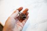 Vintage African bronze instrument held in hand to show its small, handmade scale.