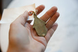 Vintage bronze hut pendant held in hand, showing its reverse side and scale.