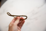 Handmade bronze African artifact held to show its organic curve and aged surface.