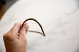 Antique African bronze artifact held in hand to show its shape and scale.