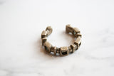 Open cuff shape of the antique African silver bracelet showing its geometric links and patina.