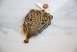 Angled view of the vintage bronze owl medallion highlighting its textured patina.