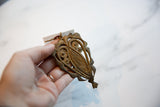 A hand holding the vintage abstract bronze owl medallion to show its scale and patina.
