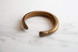 The curved profile and warm gold patina of the handmade African bronze cuff.
