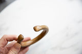 Antique bronze snake cuff bracelet held to show its C-shape and profile.