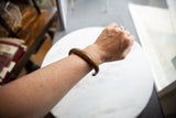 The antique African bronze snake cuff bracelet with a gold patina worn on an arm.