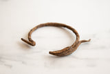 Antique African iron antelope bracelet showing its rugged, patinaed brown texture and sculpted end.