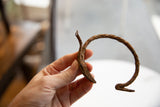 Hand holding the antique African iron bracelet, highlighting its curved form and rich patina.