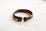 Detail of the antique bronze snake cuff's open design and aged, smooth texture.