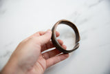Antique African bronze cuff held in hand to show its solid scale and form.