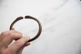 Antique bronze snake cuff held in hand, highlighting its simple form and aged patina.