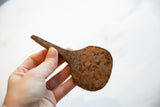 Rustic, hand-forged African iron utensil with rich brown patina and texture.