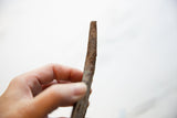 Vintage African iron utensil's side view, highlighting its aged texture and dark patina.