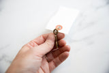 Vintage African bronze pendant held in hand, showing its small scale and handmade quality.