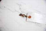 Abstract bronze pendant with a dark patina attached to a small white tag.