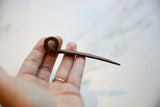 Side profile of the vintage iron pick held to show its handmade texture and size.