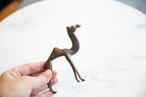 Vintage dark bronze African camel sculpture held in hand, showing its broken tail.