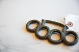 Side view of vintage African bronze knuckles showing their textured, handmade form and tag.