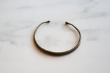 The open cuff shape and snakeskin design of an antique bronze African bracelet.