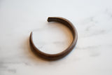 Side profile of the antique African copper cuff bracelet showing its curved form.