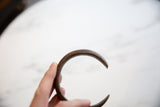 The curved silhouette and aged copper texture of the antique snake cuff.