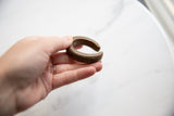 Hand holding an antique bronze cuff to show its scale and time-softened patina.