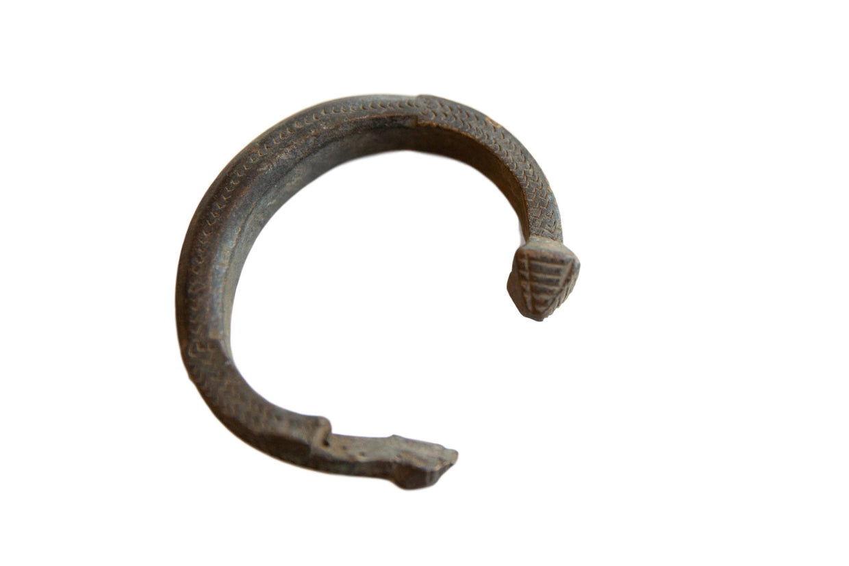 Antique African bronze snake cuff bracelet with an etched scale texture and dark, aged patina.