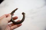 Hand holding the antique bronze African snake cuff, showing its form and textured surface.