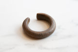 The substantial, curved form of an antique African copper cuff with a textured patina.