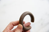 Antique copper cuff held in hand, showing its substantial form and textured patina.