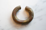 Aged copper and bronze patina on an antique African bracelet with a hand-dotted spiral design.