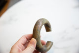 Antique copper and bronze bracelet held to show its curved form and textured patina.
