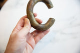 Antique African copper and bronze bracelet held, highlighting its substantial form and texture.