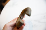 Detail showing a split and the time-softened patina on the antique bronze bracelet.
