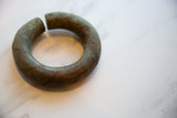 Angled view of an antique African bronze bracelet showing its etched barber pole design.