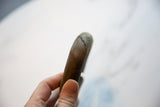 Close-up showing the tactile, spiraling design on the antique African bronze bracelet.