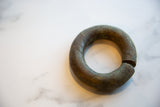 Antique African currency bracelet showing its open, circular form and time-worn patina.