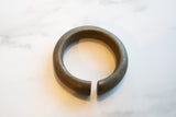 The antique bronze bracelet's open cuff, highlighting its substantial form and textured patina.