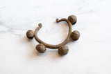 Vintage African copper alloy Lobi bracelet, textured band and bell with cross pattern.