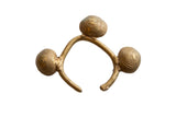 A vintage African Lobi bell cuff bracelet showing three textured bronze bells and a gold patina.