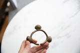 A vintage African Lobi bell cuff bracelet held to display its handmade form and size.