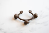 The open shape and etched bell details of a vintage Lobi bronze alloy cuff.