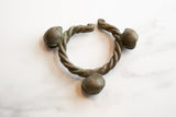 The twisted bronze body and three bell ornaments of a vintage African cuff bracelet.