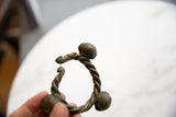Angled view of the twisted bronze Lobi cuff showing its open shape and spiral bell ends.