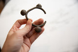 The form and aged patina of a vintage bronze Lobi bell cuff bracelet held in hand.