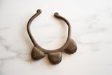 A vintage bronze cuff bracelet with three prominent, rounded bell features.