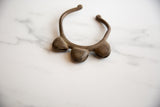 Angled view of a vintage African bronze cuff bracelet highlighting its three bell forms.