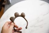 Vintage African bell cuff bracelet with an aged bronze patina held to show its scale.