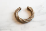 Overhead view of an antique African aluminum cuff bracelet with a twisted design and aged patina.